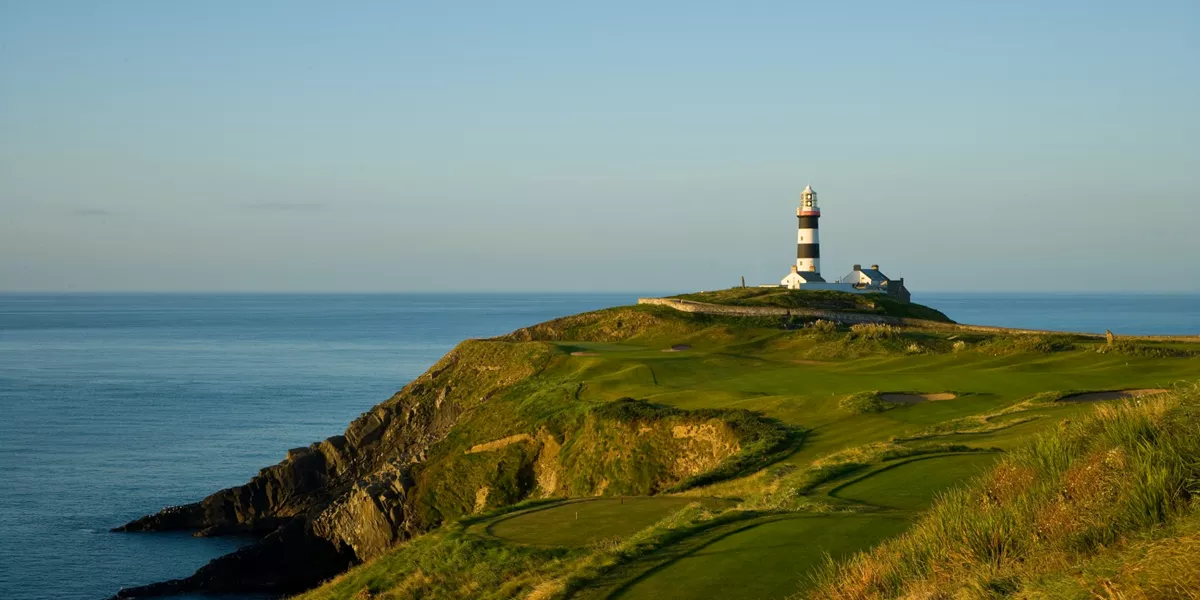 A lighthouse on top of a hill near the ocean