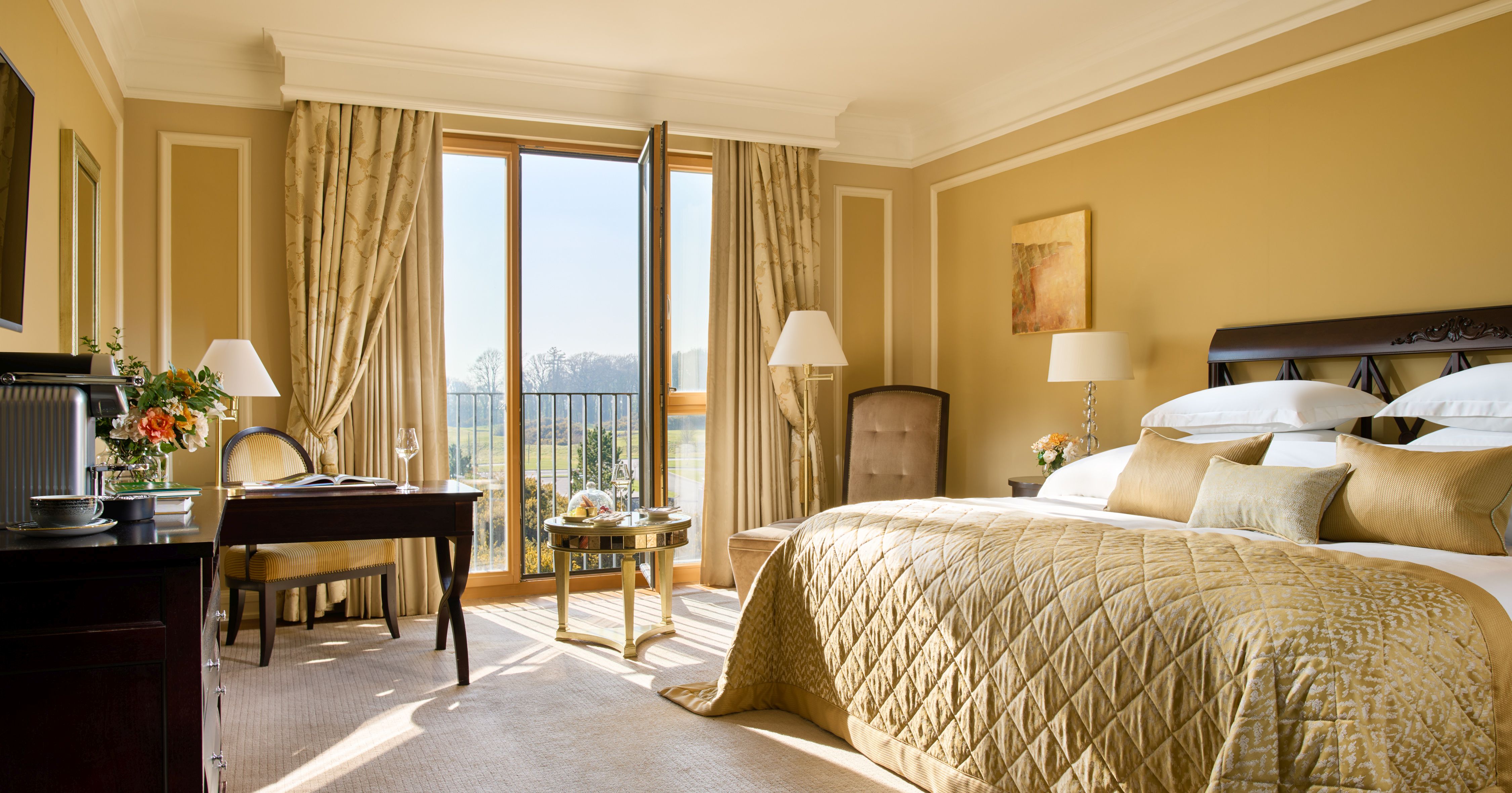 A deluxe bedroom with a large bed and a balcony in Castlemartyr Resort in Ireland 