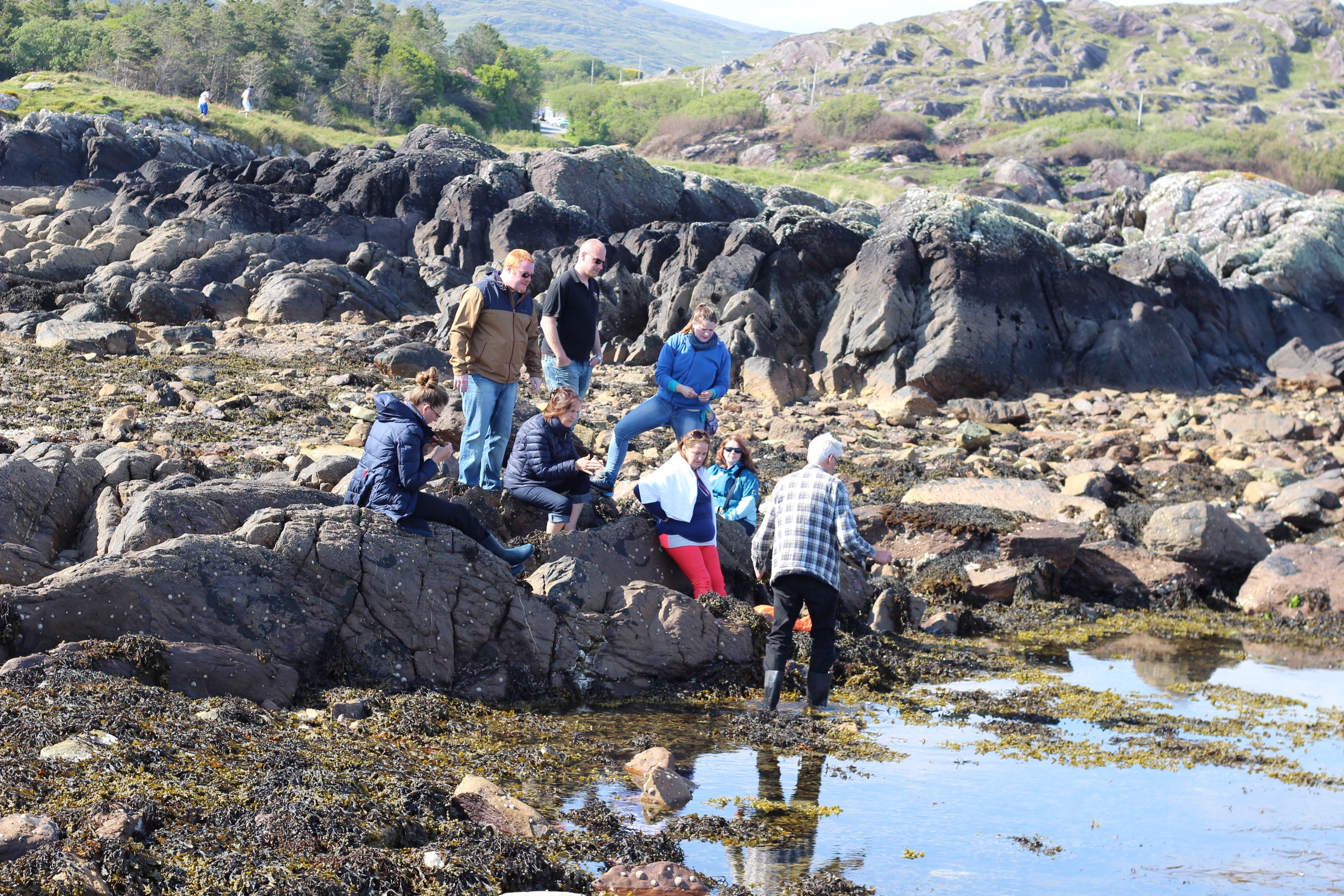A group of people sat down by the rocks in the country side