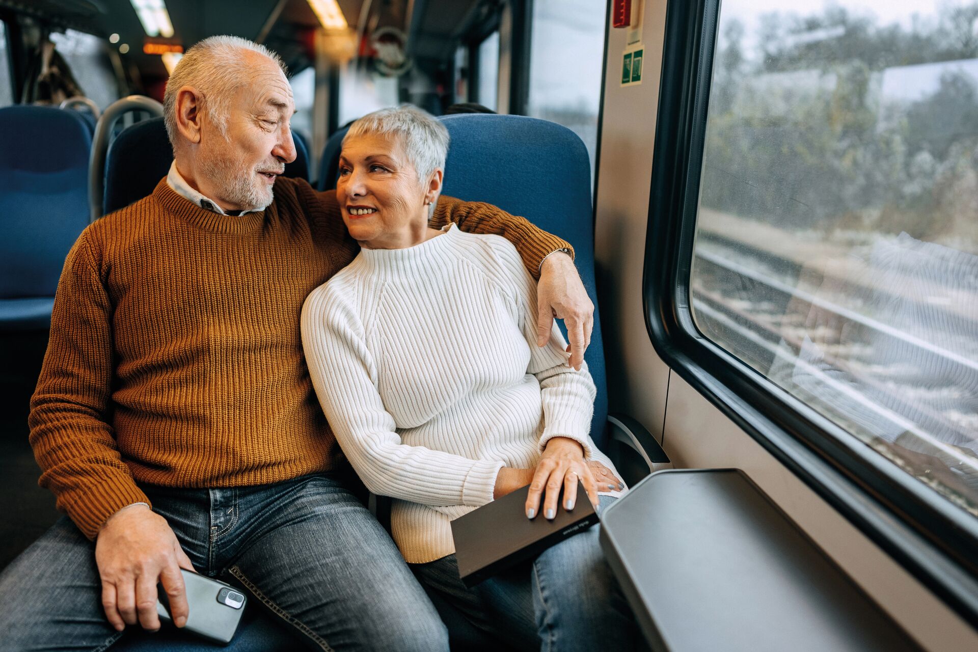 A man and woman are passengers on a train on a vacation.