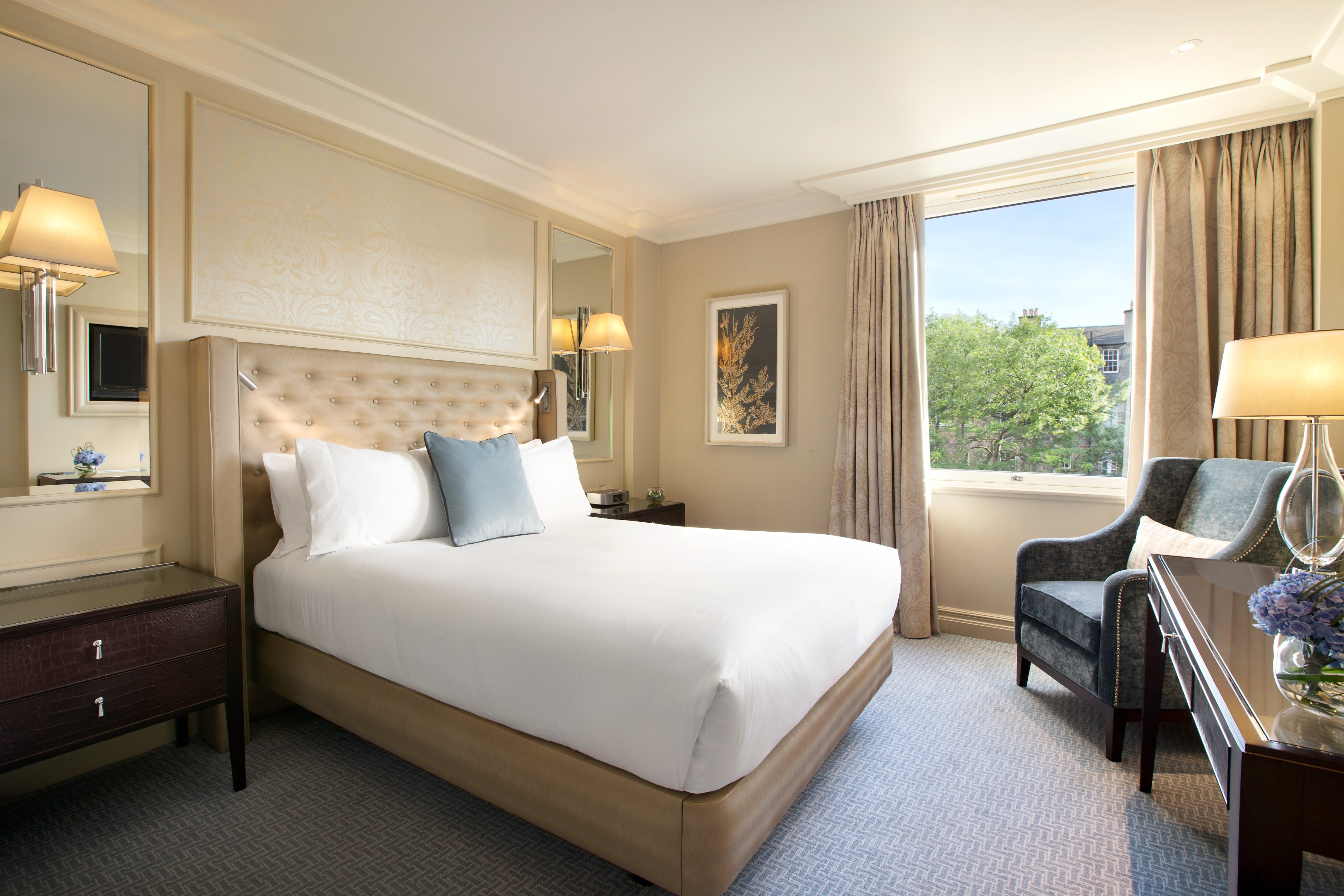Deluxe room with a large bed, chairs and city view in Waldorf Astoria in Edinburgh
