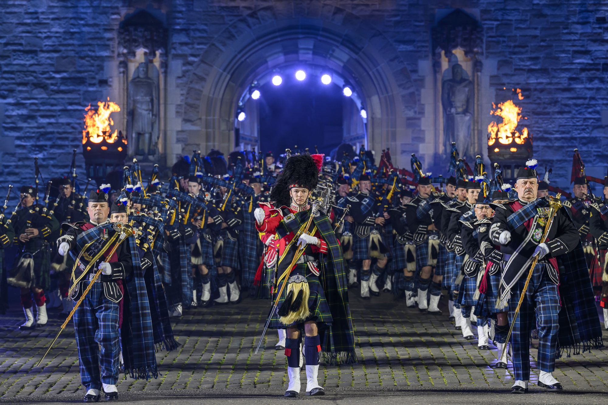 A group of men in kilts marching down a street during the Royal Edinburgh Military Tattoo event