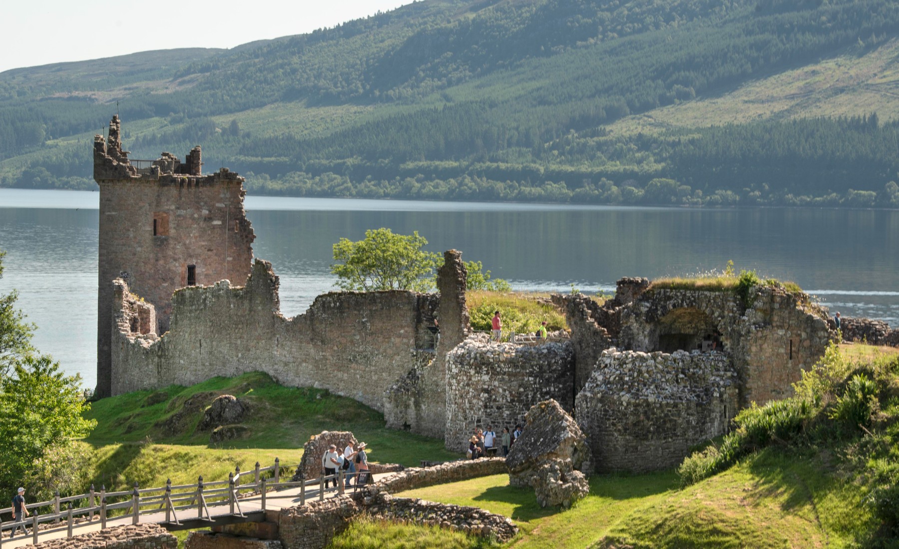 Castle ruins next to a lake and mountains 