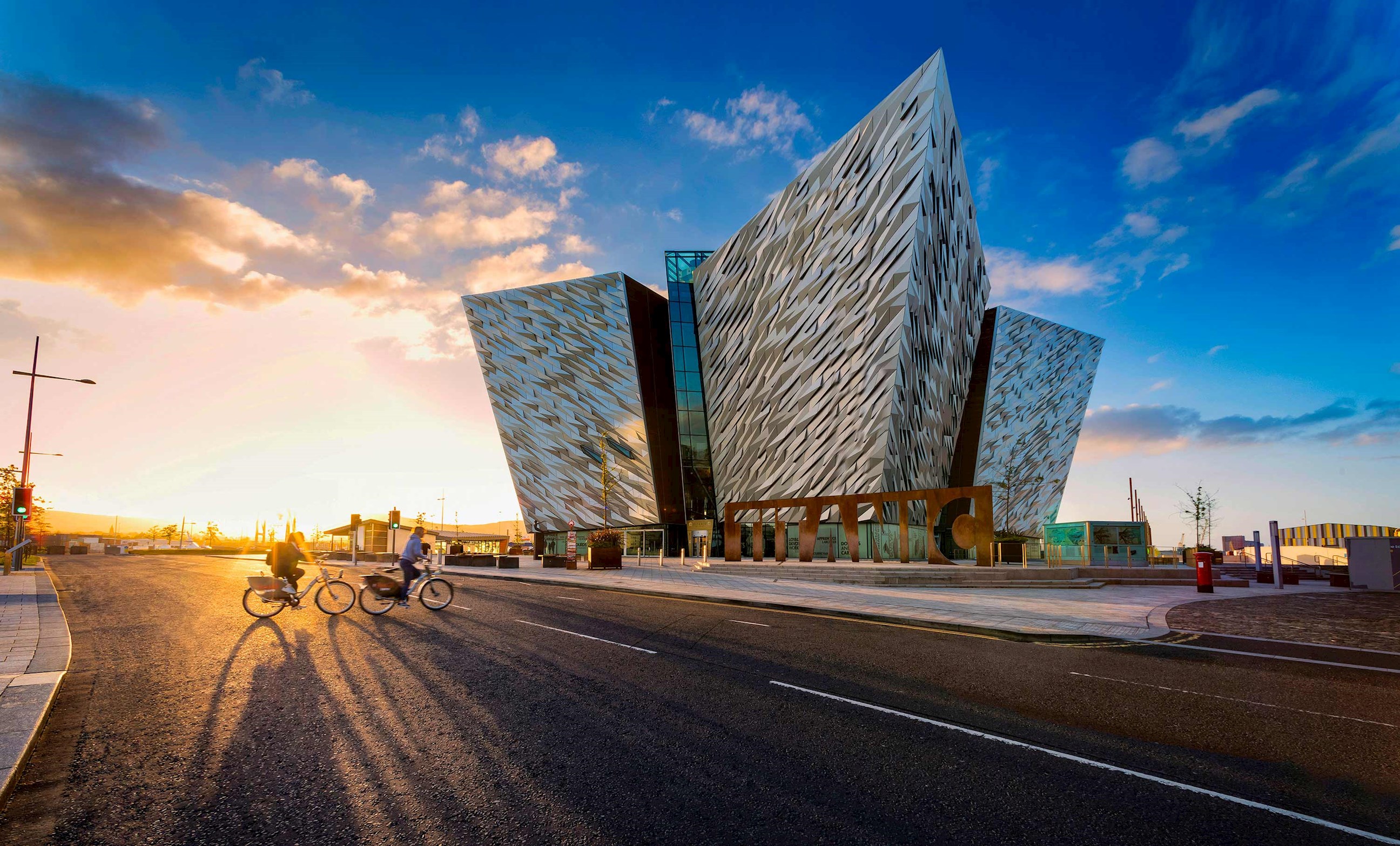 Titanic Belfast museum with cyclists at sunset in Northern Ireland