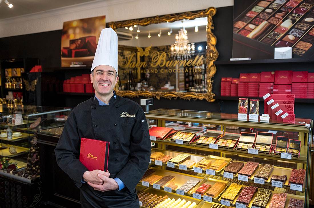 A chocolatier posing with chocolate display