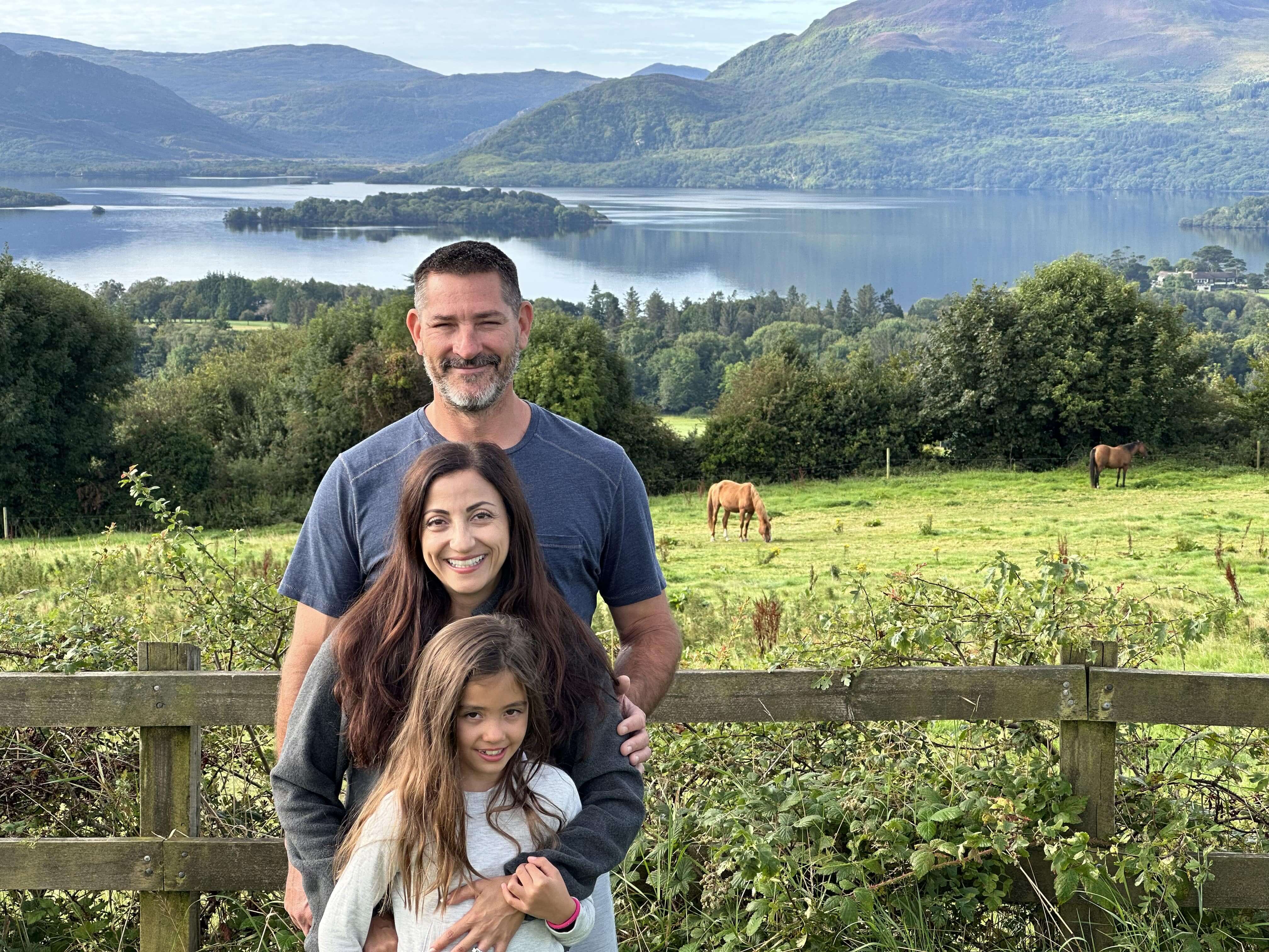 A man and two girls standing in front of a fence