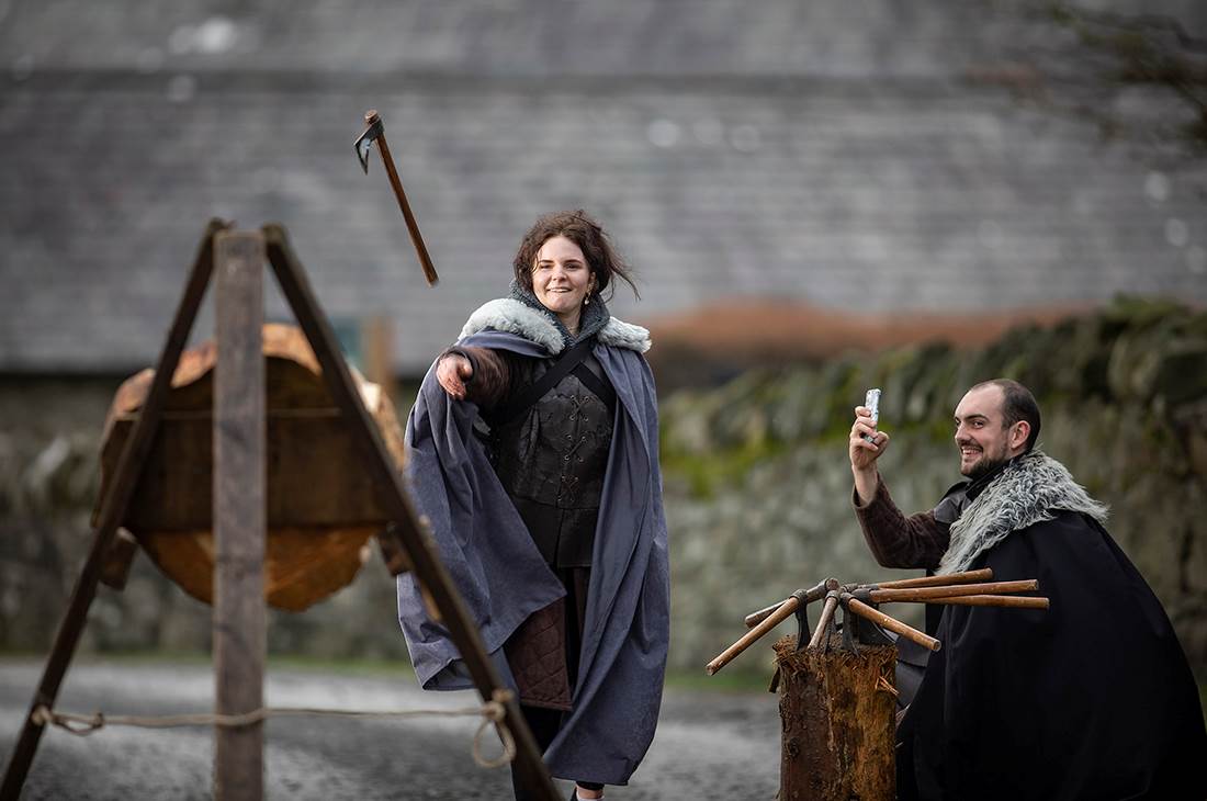 Woman throwing axe while being photographed