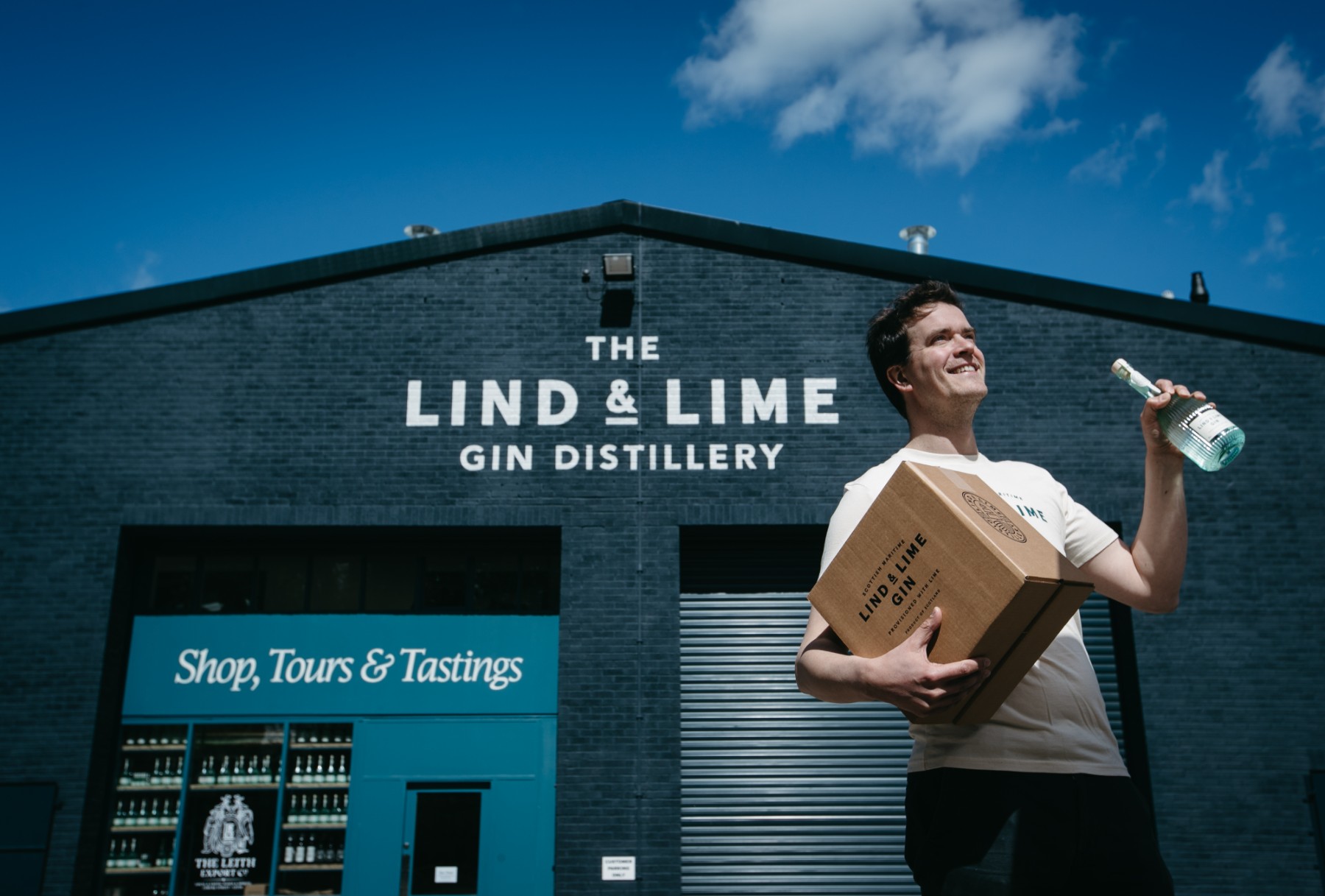 Lind & Lime outside with man holding a box and a bottle