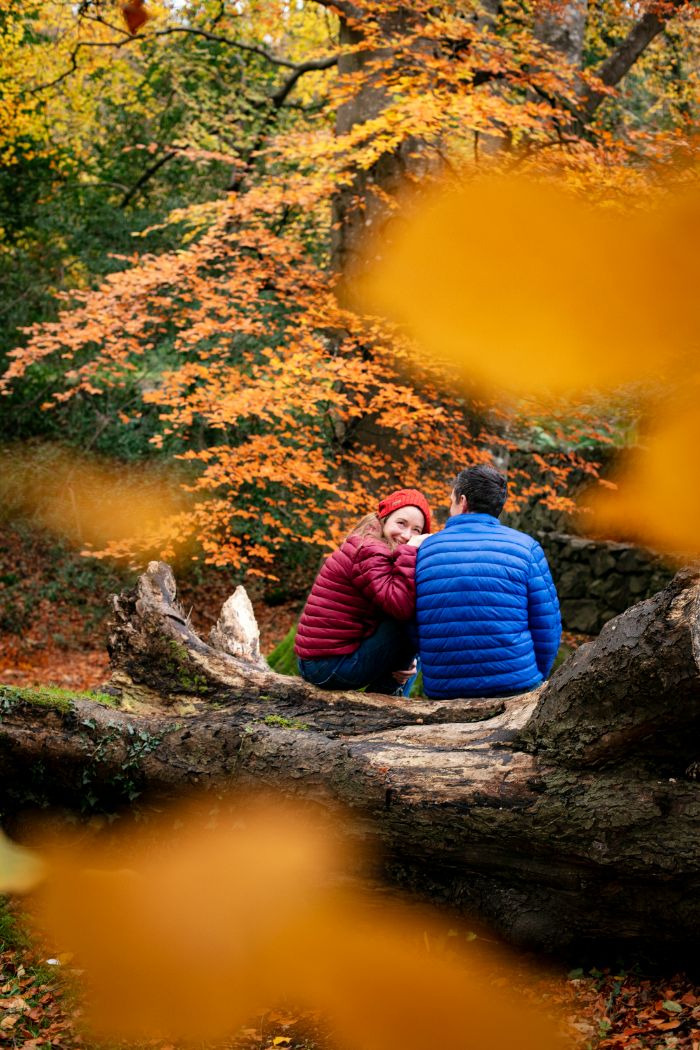 Two people sitting on a log in the woods during autumn