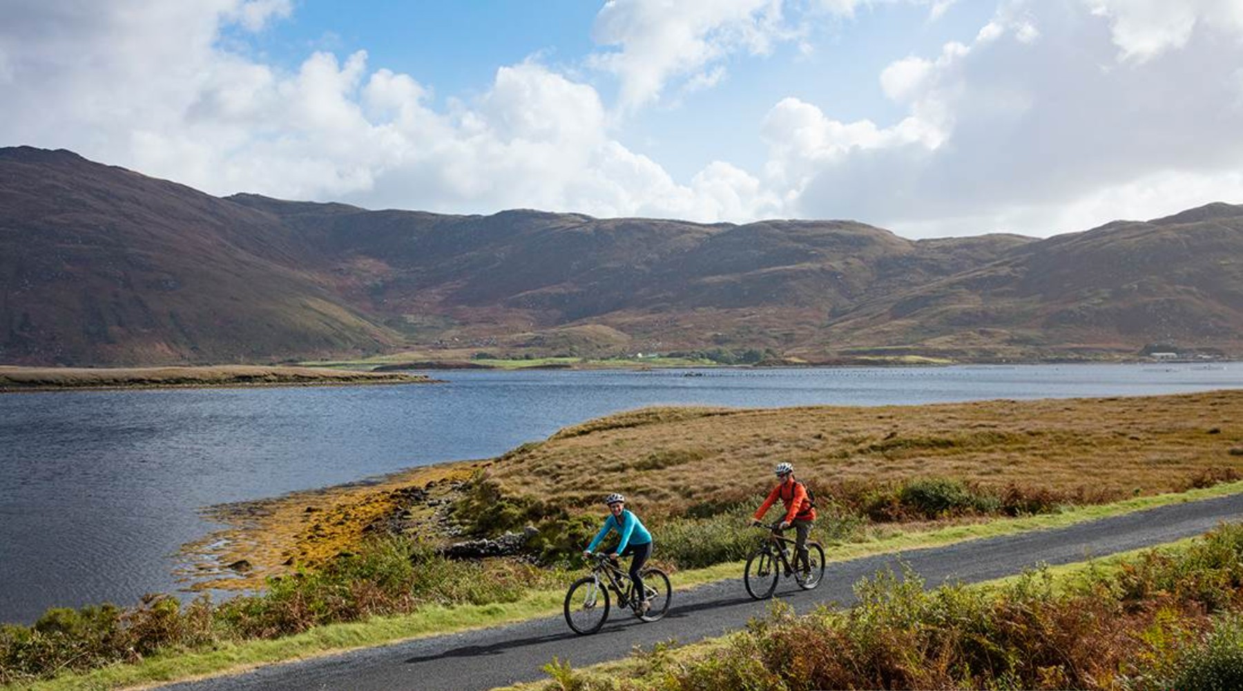 People riding bike through mountains in Killarney National Park, Ireland