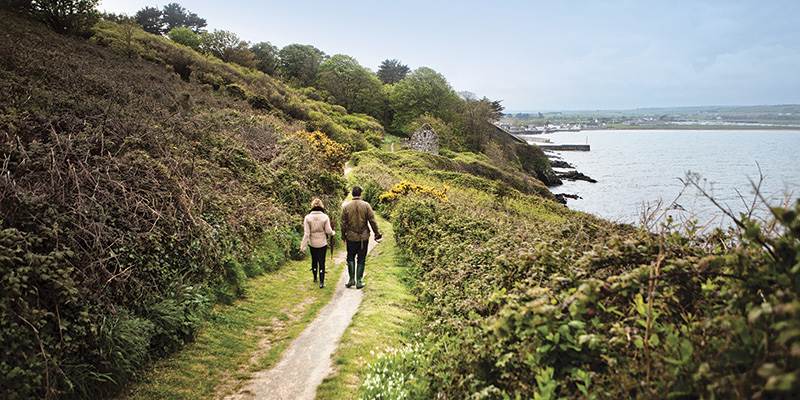 Couple walking along a country path next to the sea