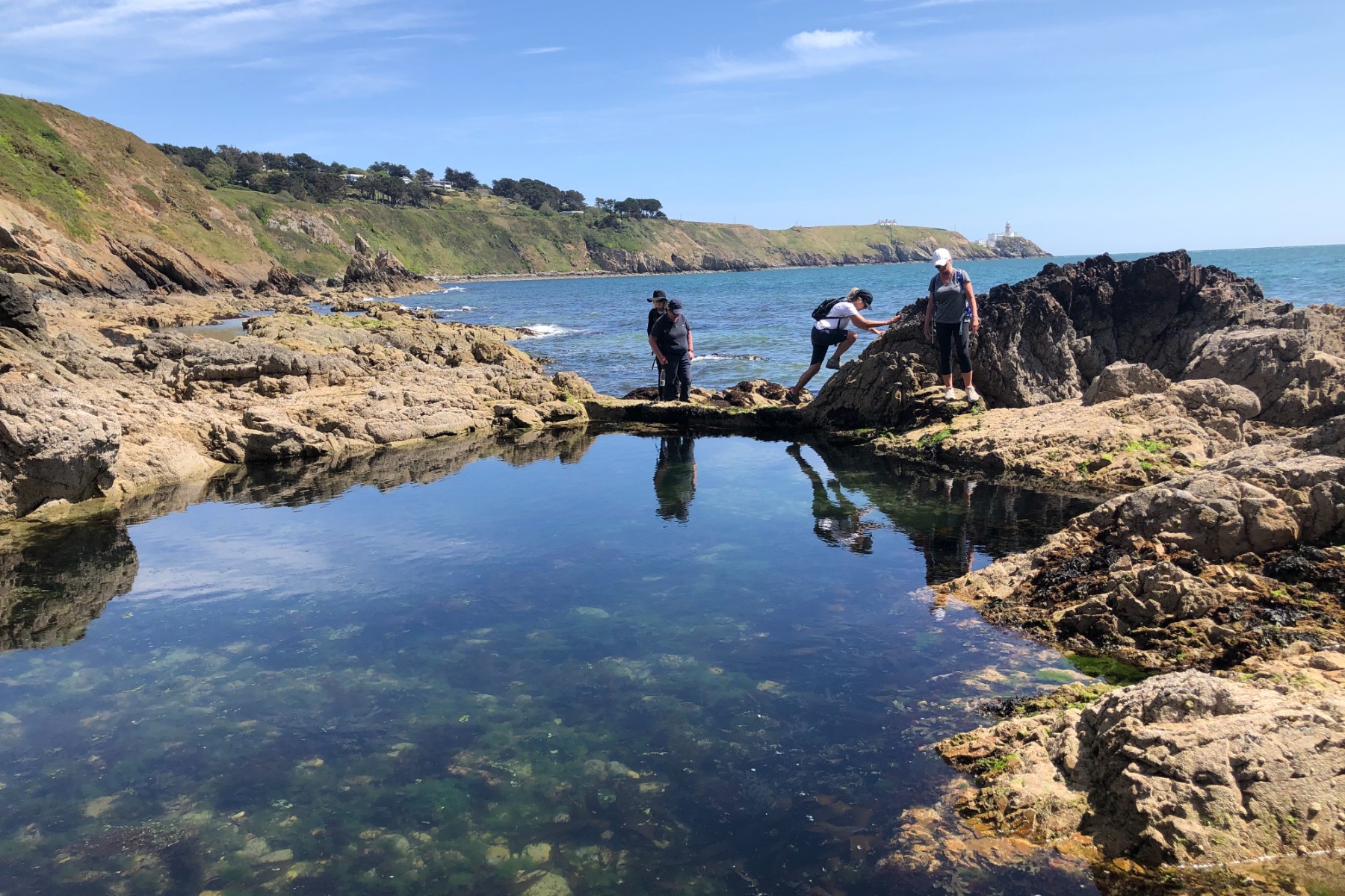 A couple of people standing on top of a rock formation near the water