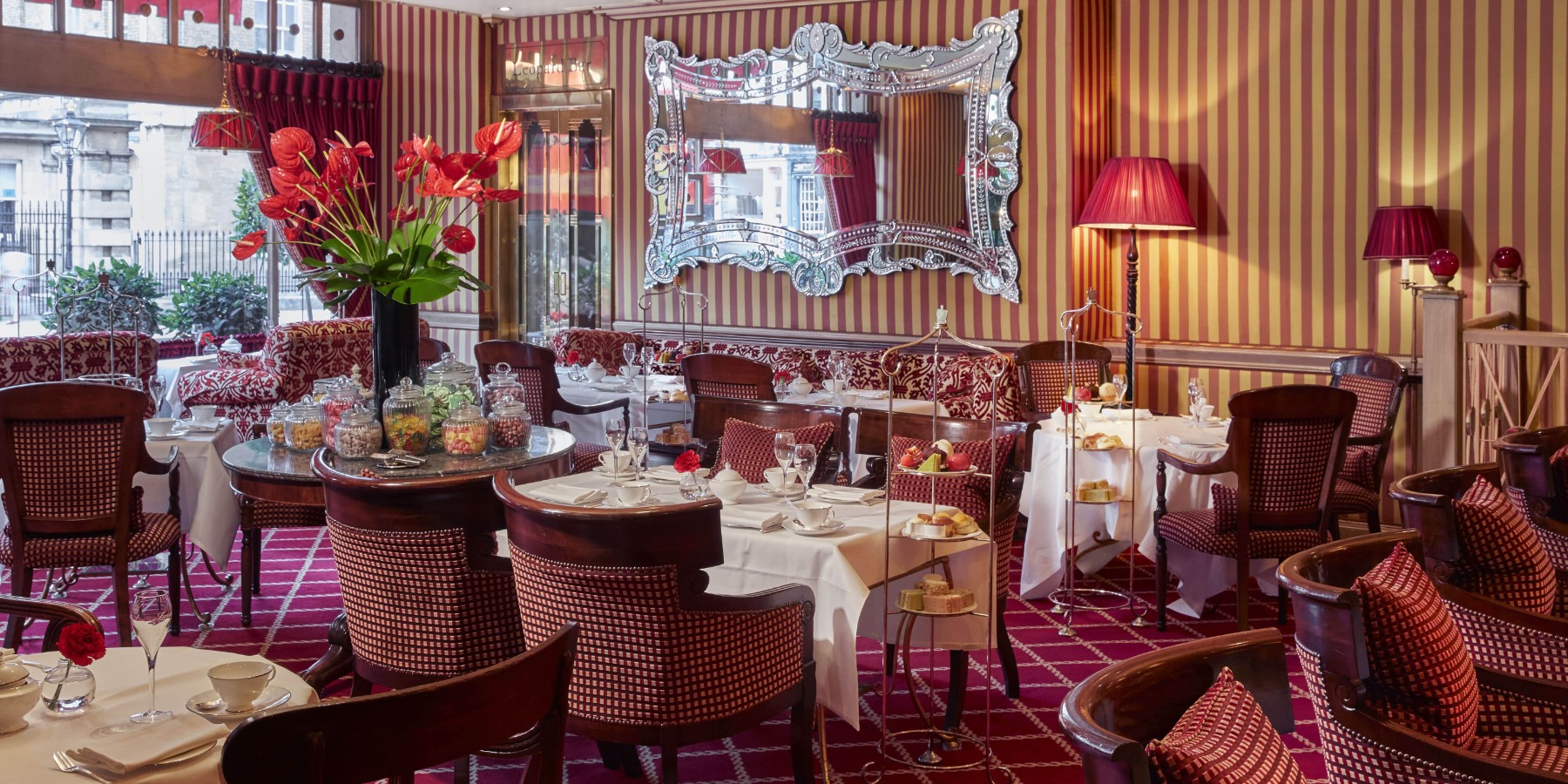A luxury dining room at the Rubens with tables, chairs, and a mirror ready for afternoon tea