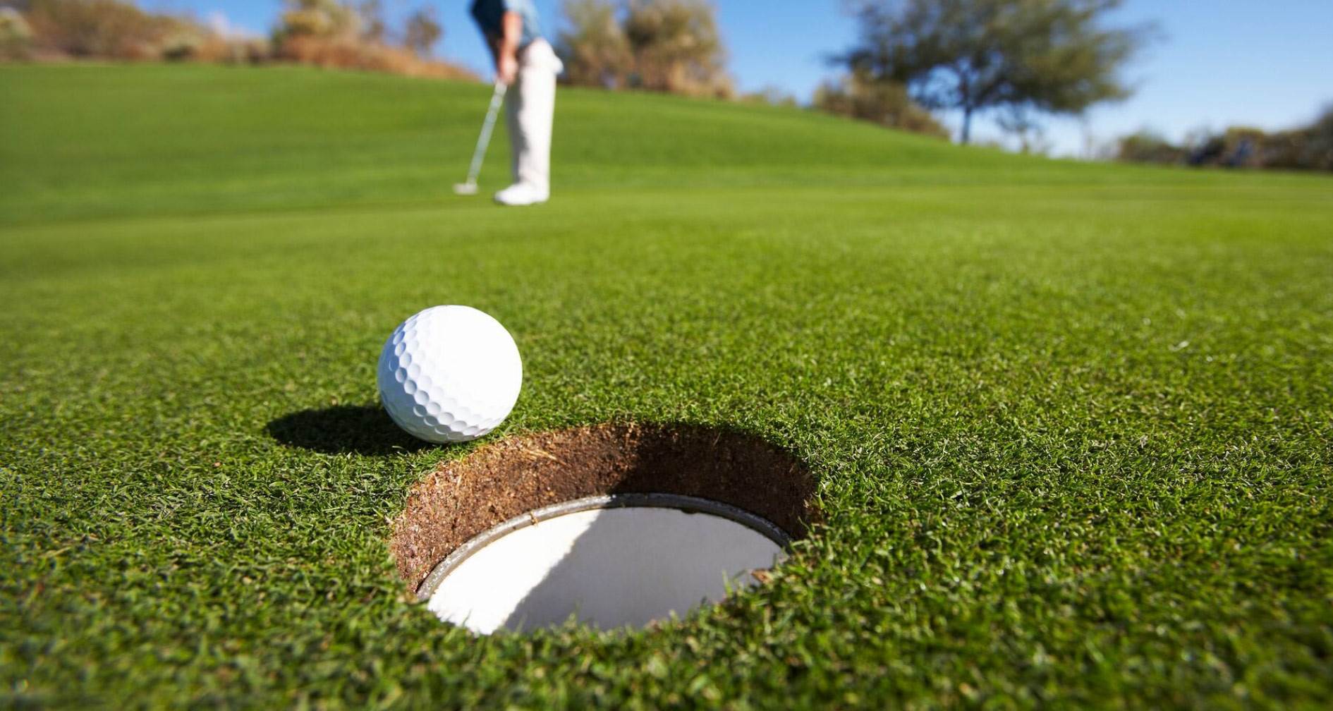 A golf ball sitting on top of a green field next to a hole
