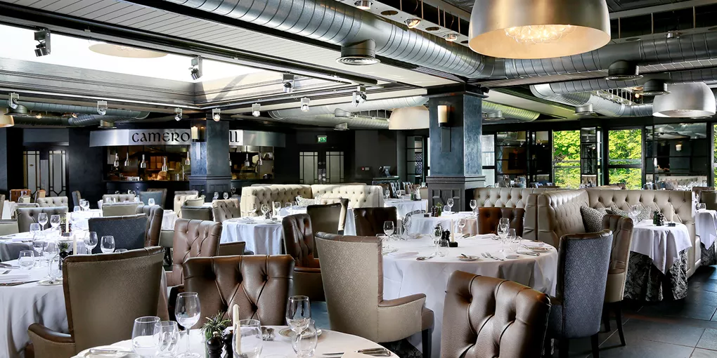 A restaurant with tables and chairs with white tablecloths