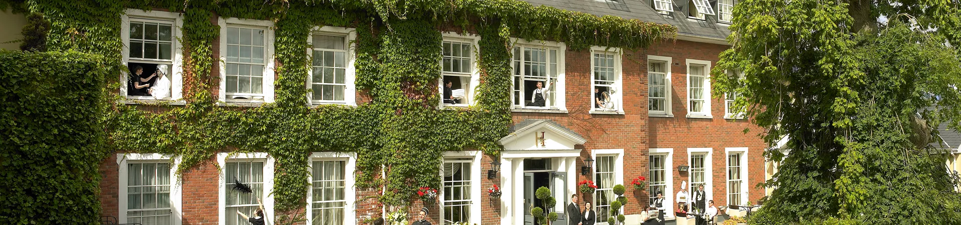 Outside image of hotel employee cleaning windows and one walking dog