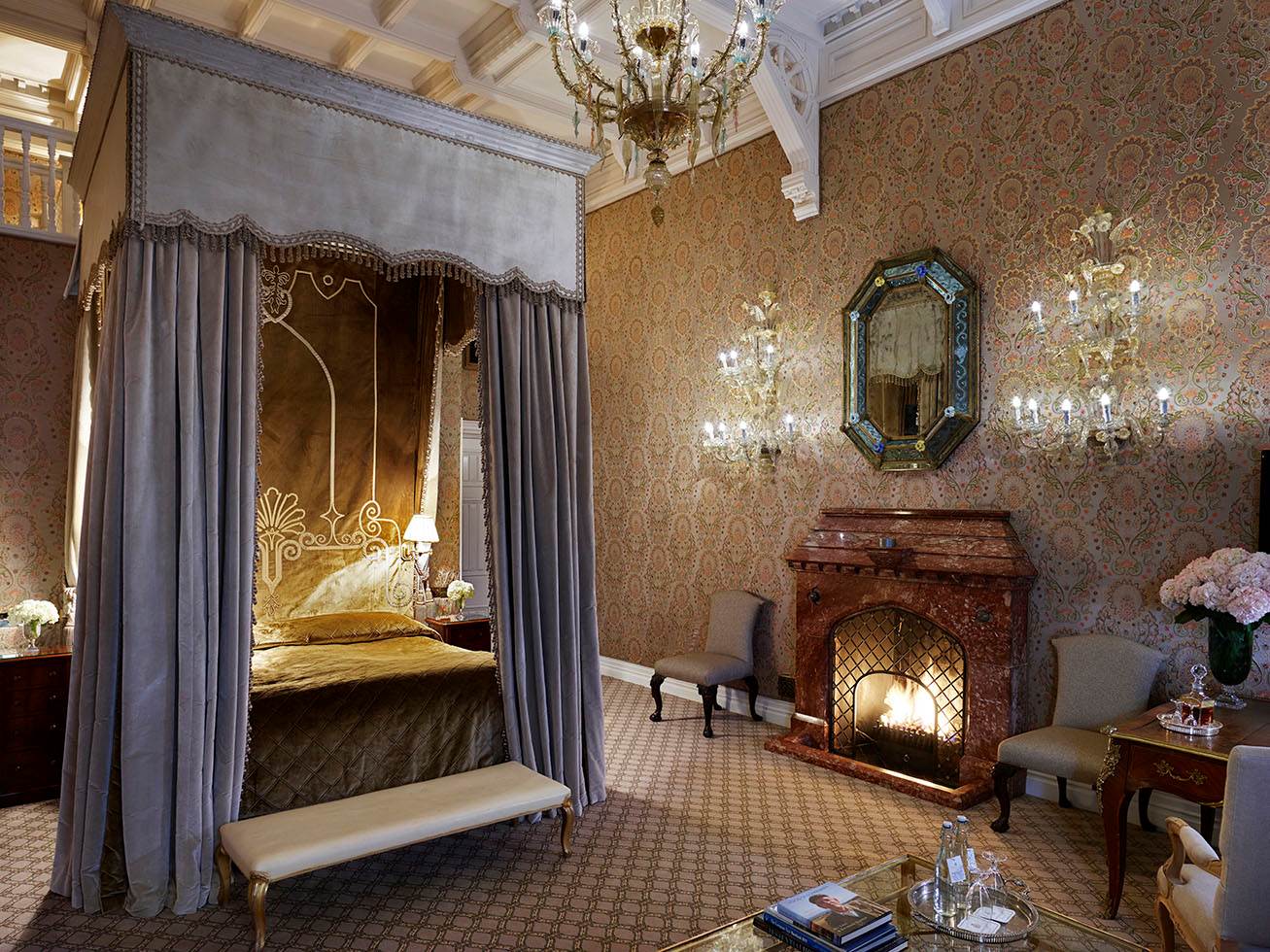 A bedroom with a fireplace and chandelier in Ashford Castle