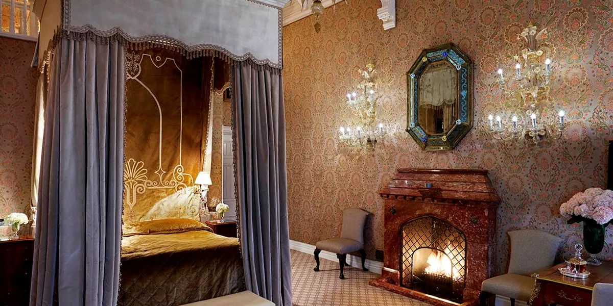 A bedroom with a fireplace and chandelier in Ashford Castle