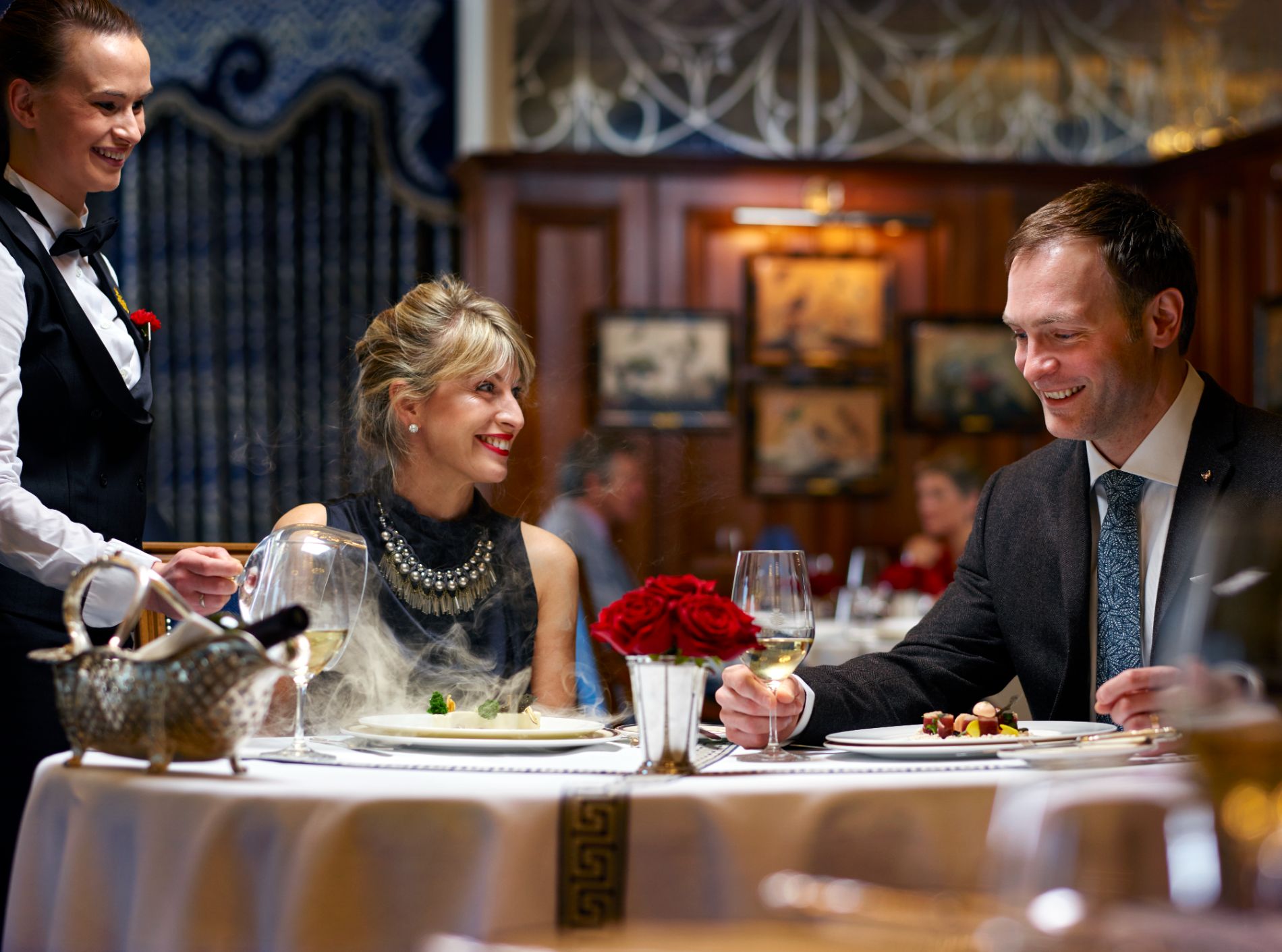 A couple of people sitting at a table with food in restaurant