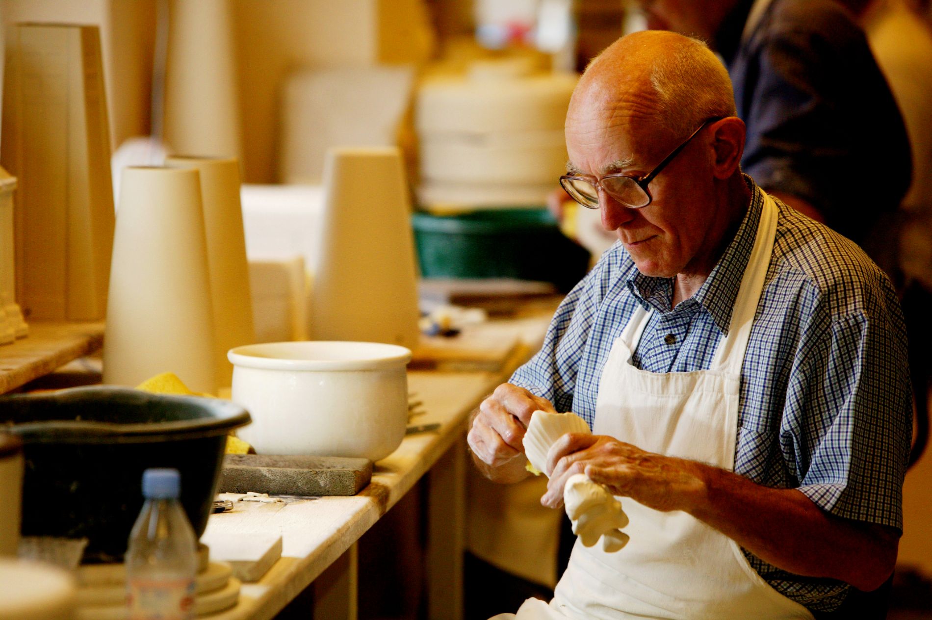 An older man in an apron is working in Bellek Pottery