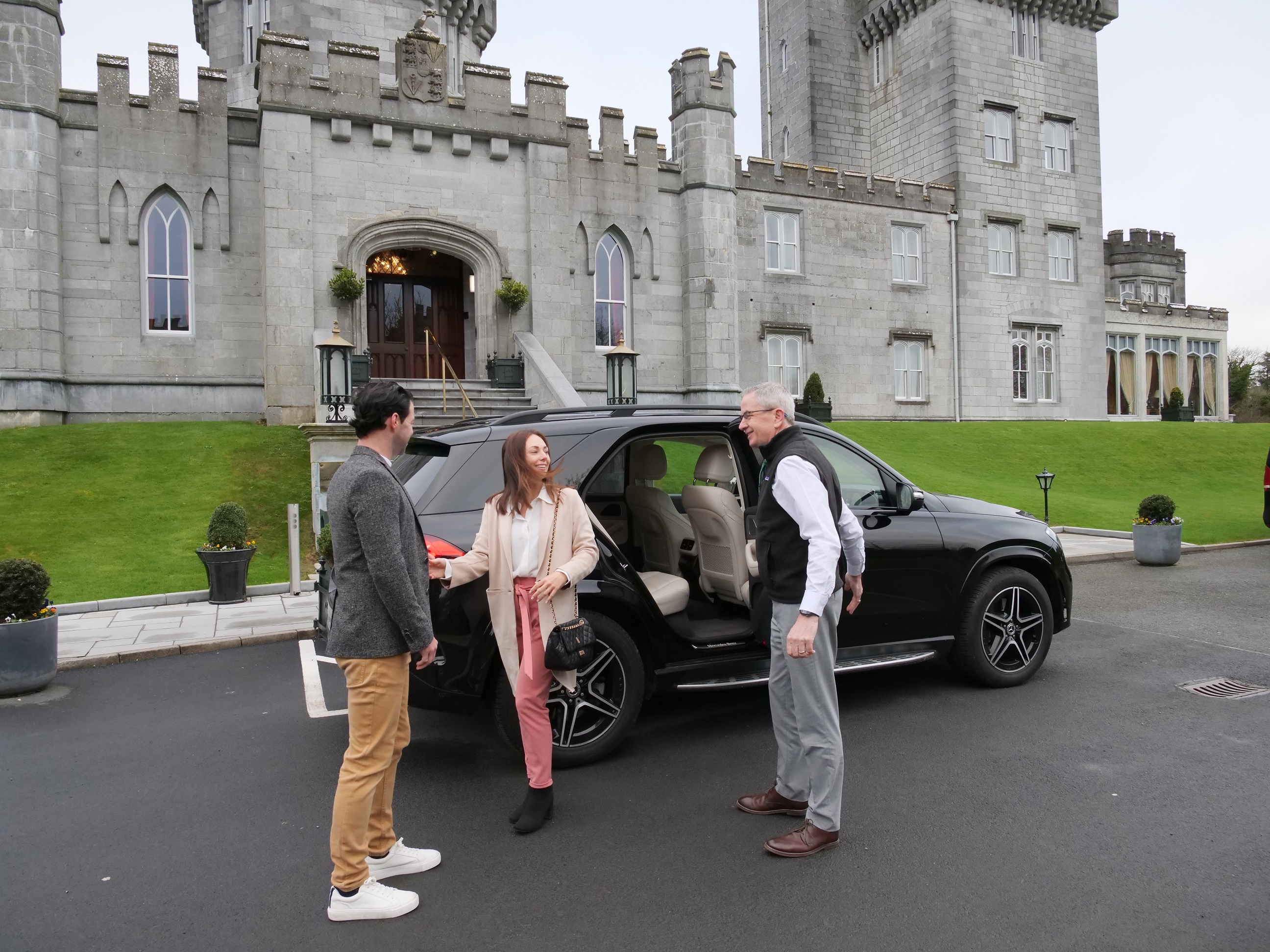 A group of people standing in front of a car